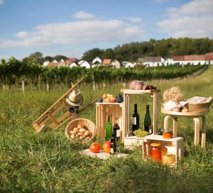 Regionale Produkte aus dem Weinviertel die auf Holzkisten aufgesellt sind, im Hintergrund ist die Kellergassen Galgenberg in Wildendürnbach zu sehen