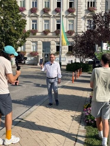 Am Bild zu sehen der Mistelbacher Bürgermeister Stubenvoll mit 2 Filmleuten beim Videodreh am Stadtplatz Mistelbach für Bewerbung der Cities App