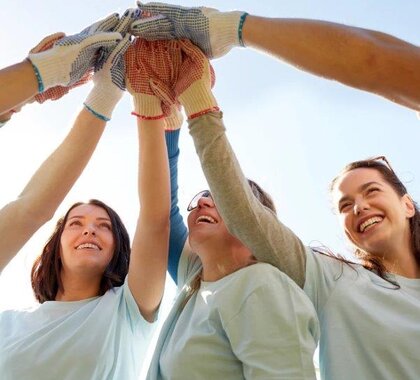 Drei Frauen halten die Hände in der Mitte zusammen und symbolisieren, dass sie zusammenhalten.