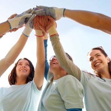 Drei Frauen halten die Hände in der Mitte zusammen und symbolisieren, dass sie zusammenhalten.