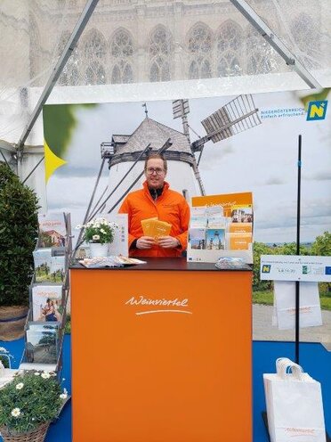 Ein Mitarbeiter von Weinviertel Tourismus am Stand beim Bike Festival. Im Vordergrund ist ein oanger Messerstand mit der Aufschrift Weinviertel zu sehen.