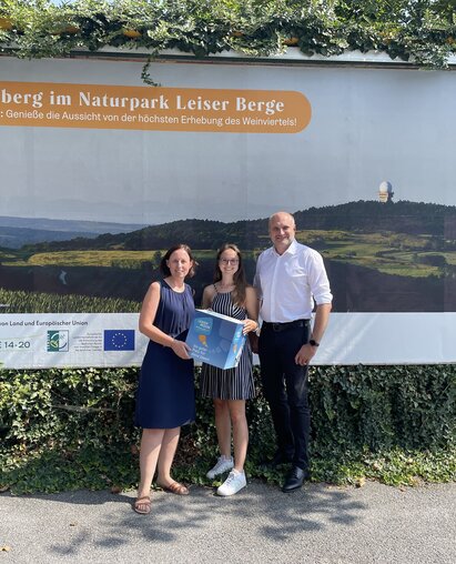 Christine Filipp (Geschäftsführerin der LEADER Region Weinviertel Ost), Caroline Fribert (Projektbegleitung LEADER Region Weinviertel Ost) und Bgm. Christian Frank (Obmann der LEADER Region Weinviertel Ost) vor einem der Großplakate.